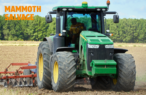 Photo of a green tractor being driven through a field with a graphical overlay of text saying MAMMOTH SALVAGE